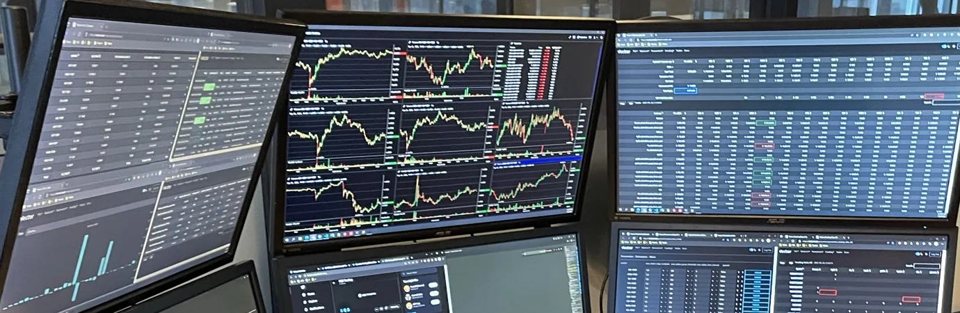 Six monitors on the SQS trading desk showing live depth charts, order books and quote tables.